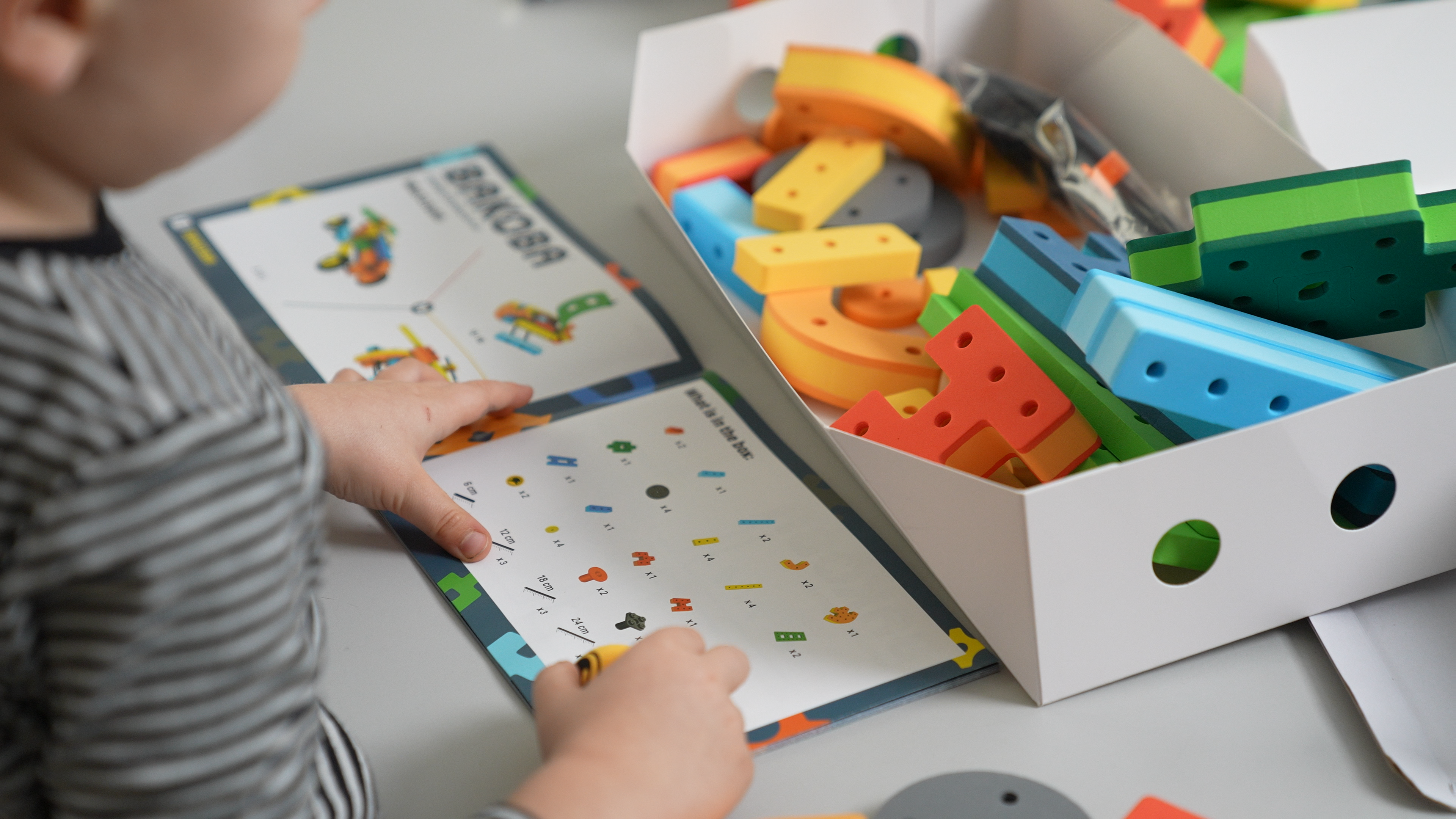 A child following a BAKOBA building guide while assembling a detailed robot model.