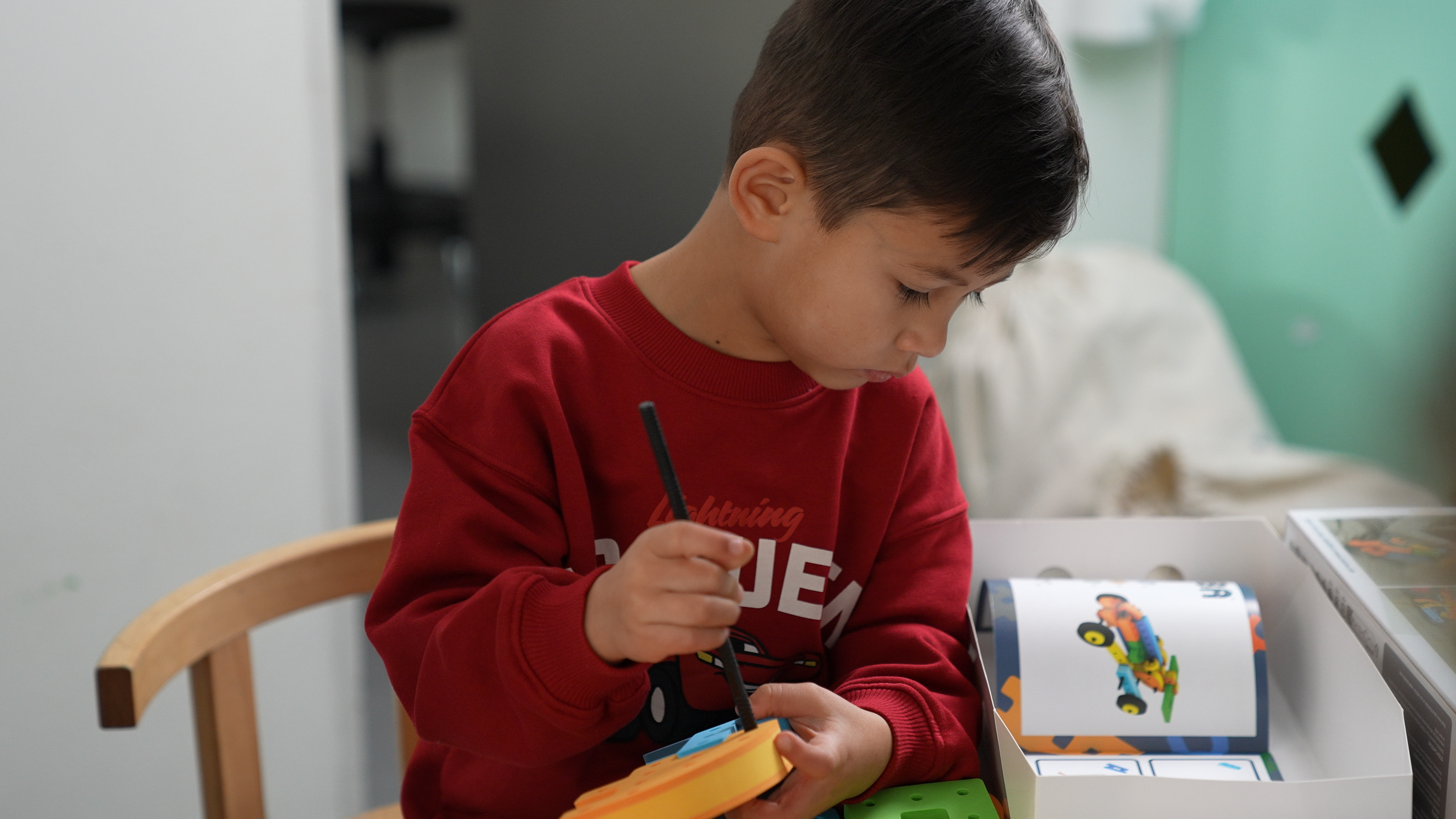 A child creating a colorful fantasy animal using BAKOBA foam blocks, demonstrating open-ended creative play.