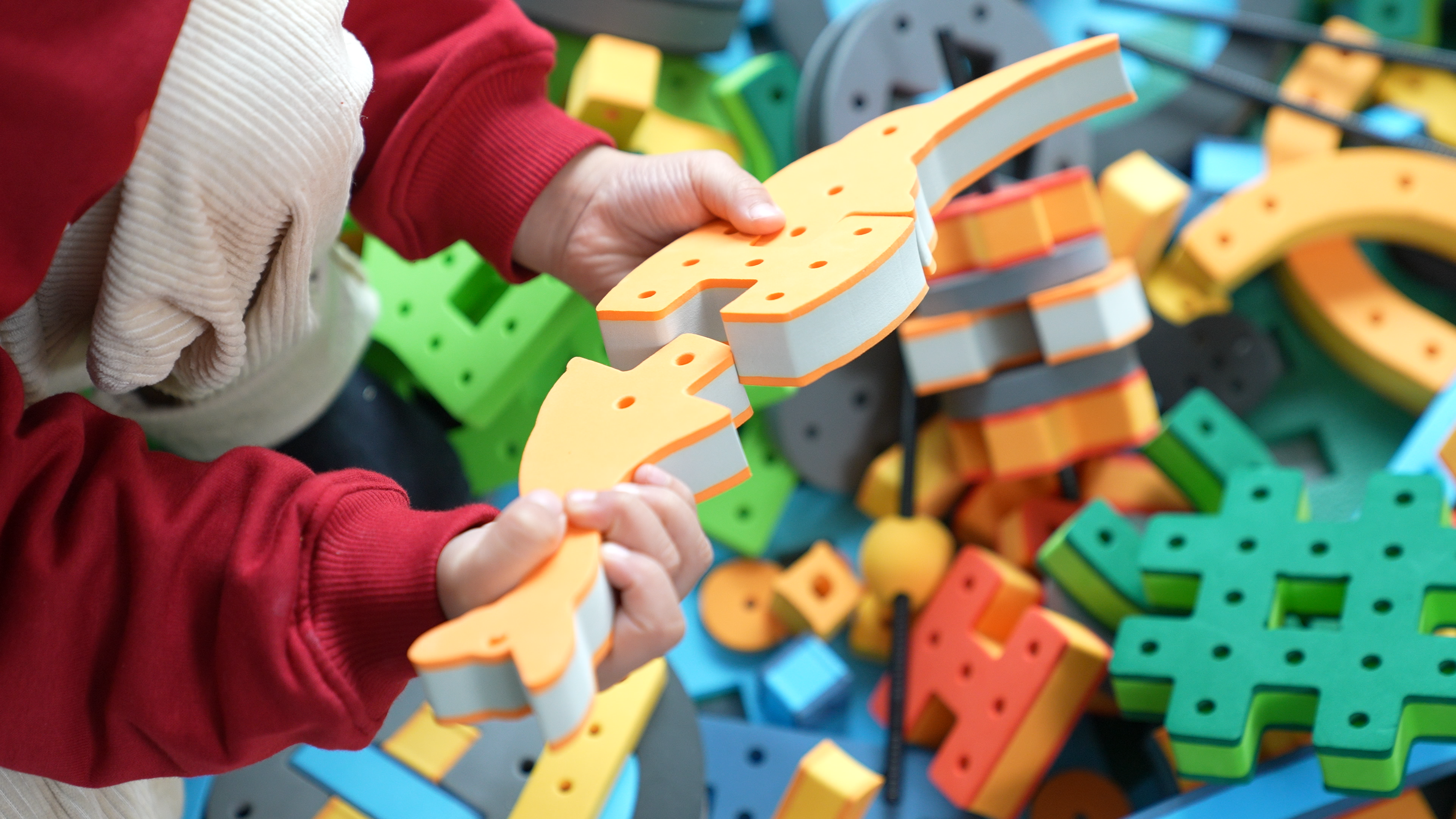 A detailed view of a child&rsquo;s hands carefully connecting soft BAKOBA elements, highlighting fine motor skill development.