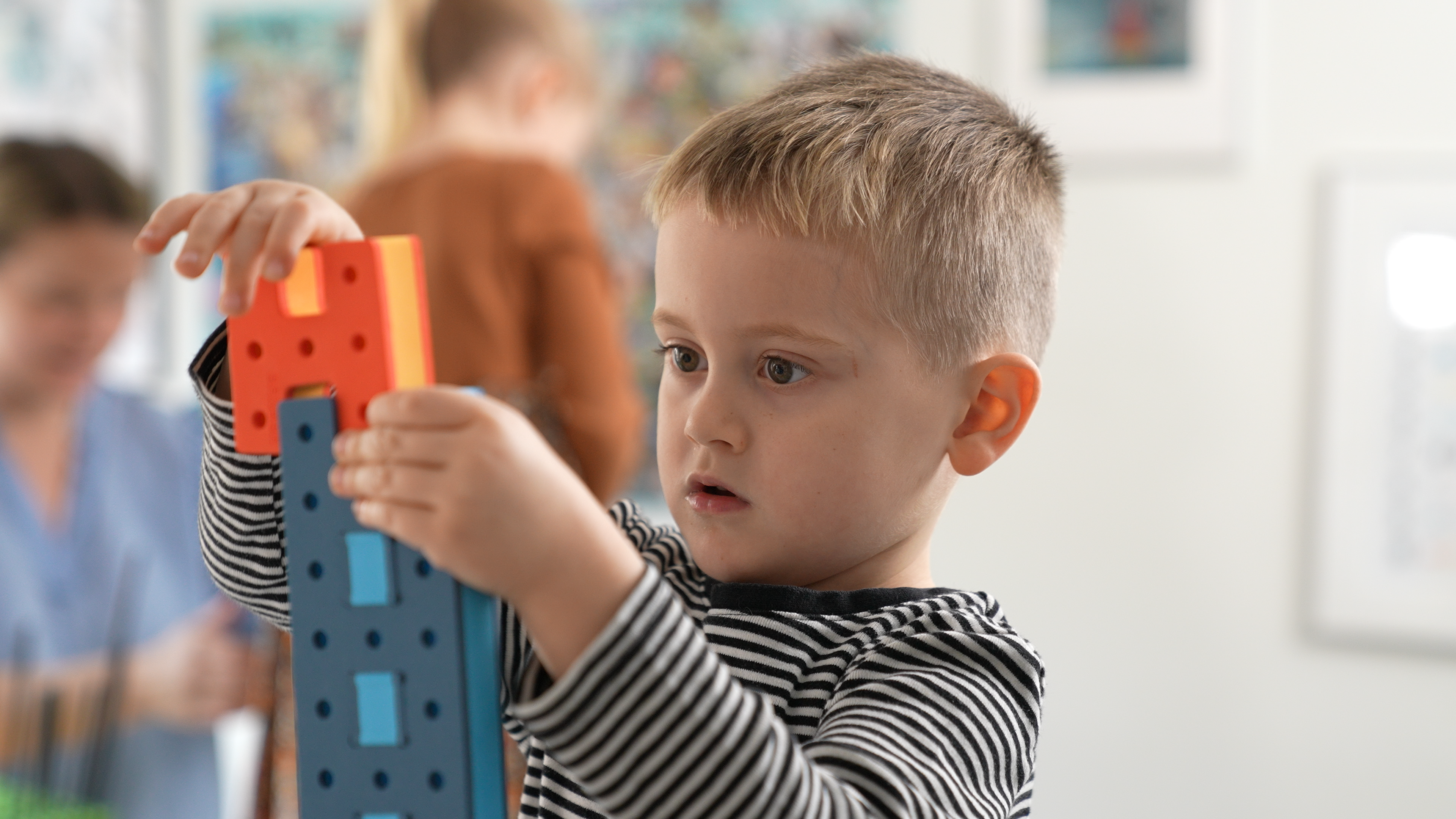 A detailed view of a child connecting BAKOBA foam elements, demonstrating fine motor skill development.